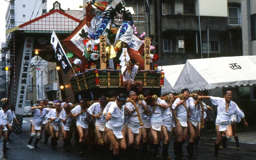 A team in white coats and loincloths running with its one-tonne float through a Hakata street, 13 July 2010