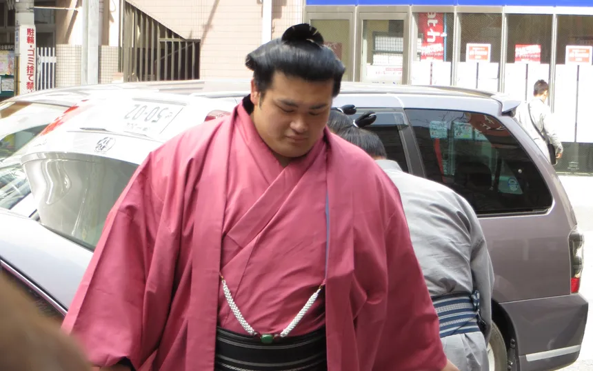 A wrestler in a pink kimono arriving at the arena during the March tournament in Osaka, 2013