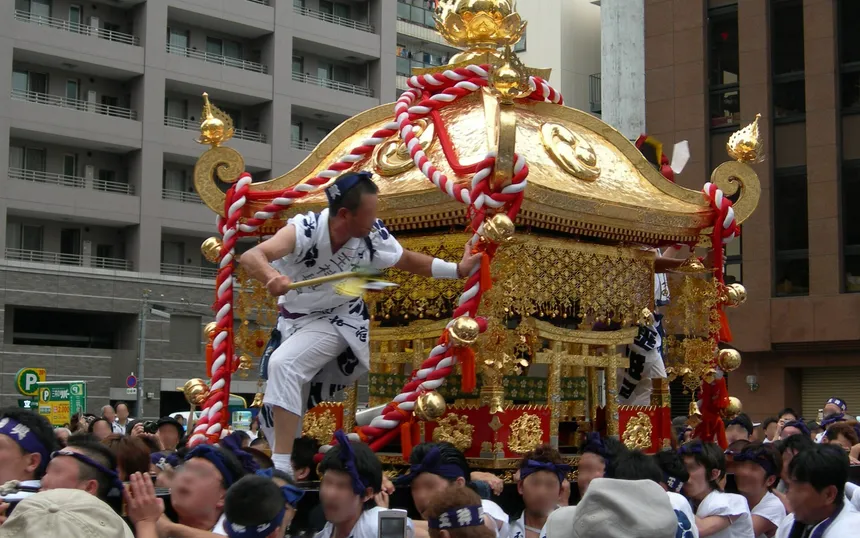 A golden mikoshi carried through the crowd in the land procession of Tenjin Matsuri