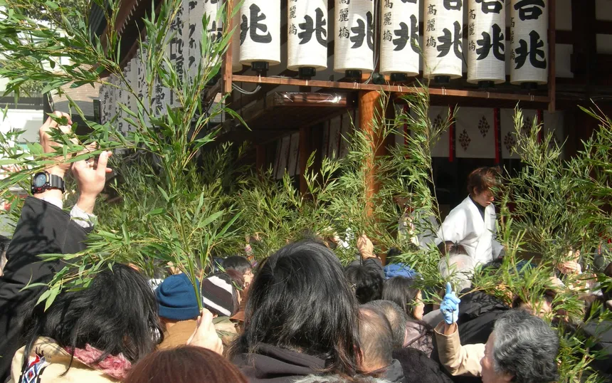 Visitors holding up bamboo branches under rows of paper lanterns at Imamiya Ebisu Shrine