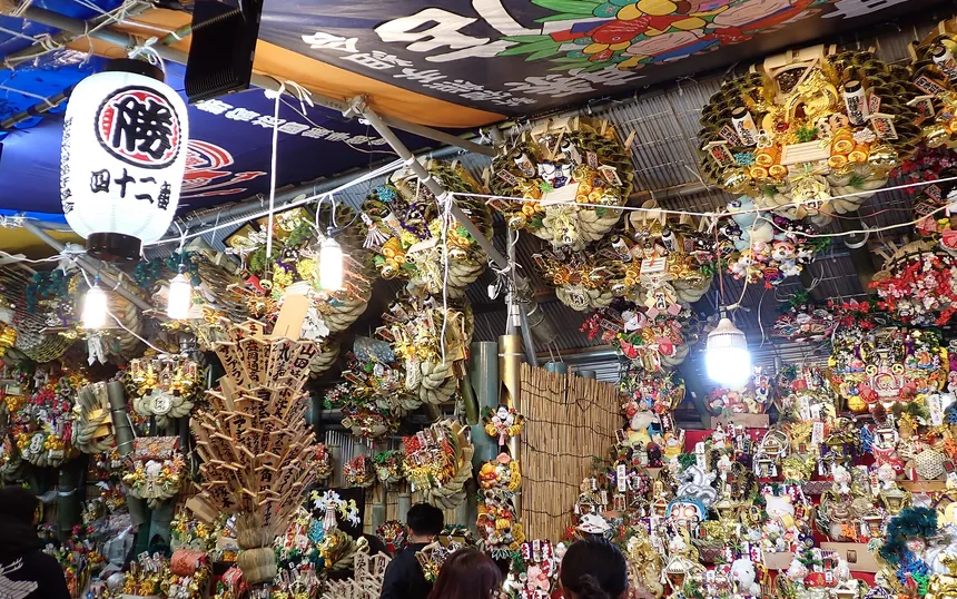 A stall stacked with kumade rakes at a rooster-day market; this one at Hanazono Shrine, Shinjuku